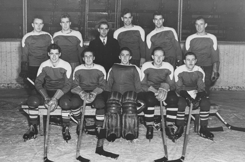 Ten men in hockey uniforms and one man in suit and tie