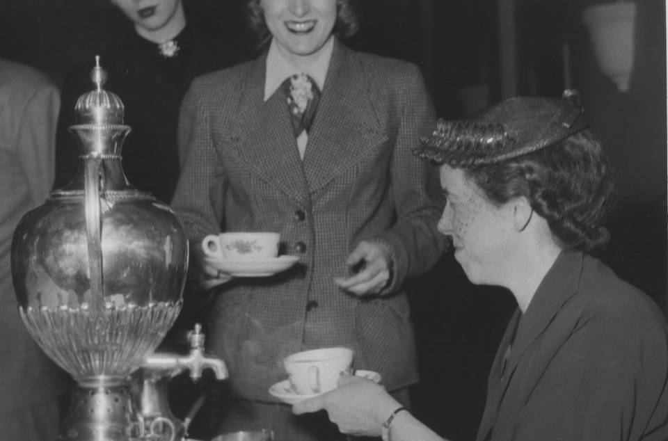 Woman serving tea from a samovar to two other women