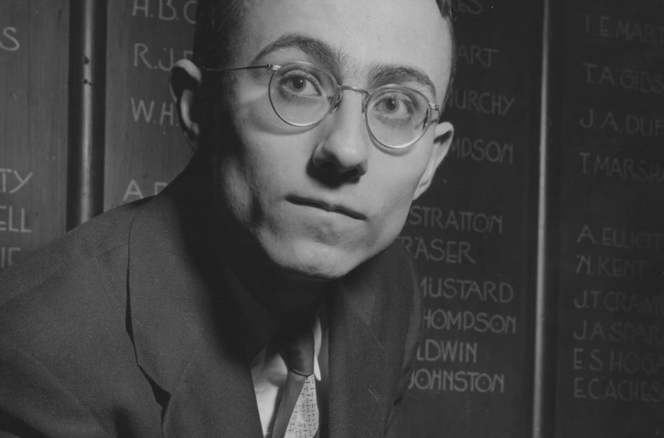 David P. Gauthier in Junior Common Room in front of list of names on wall