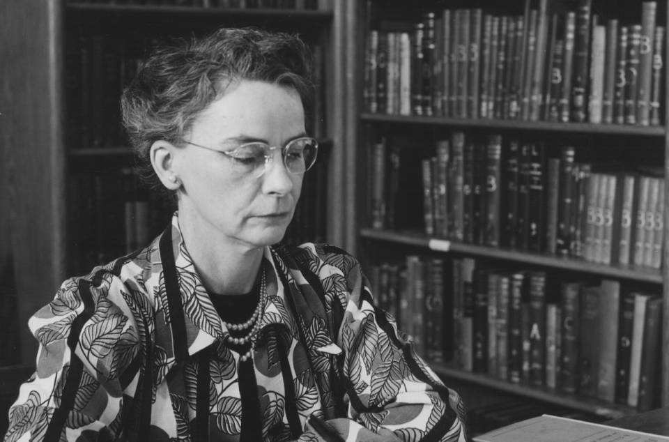 Margaret Hiltz working at desk, with shelves of books in the background