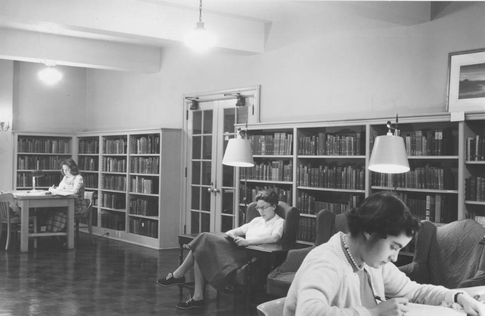 Three women studying near shelves of books