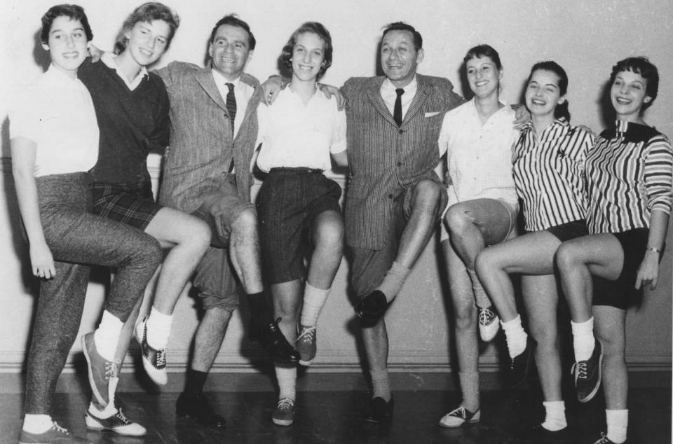 Johnny Wayne and Frank Shuster and six young women posing with one knee raised