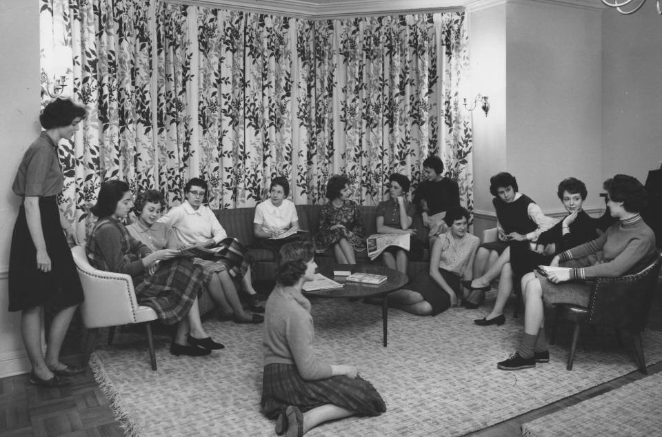 About thirteen young women sitting in a semi-circle.