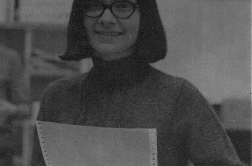 Woman seated at desk holding paper