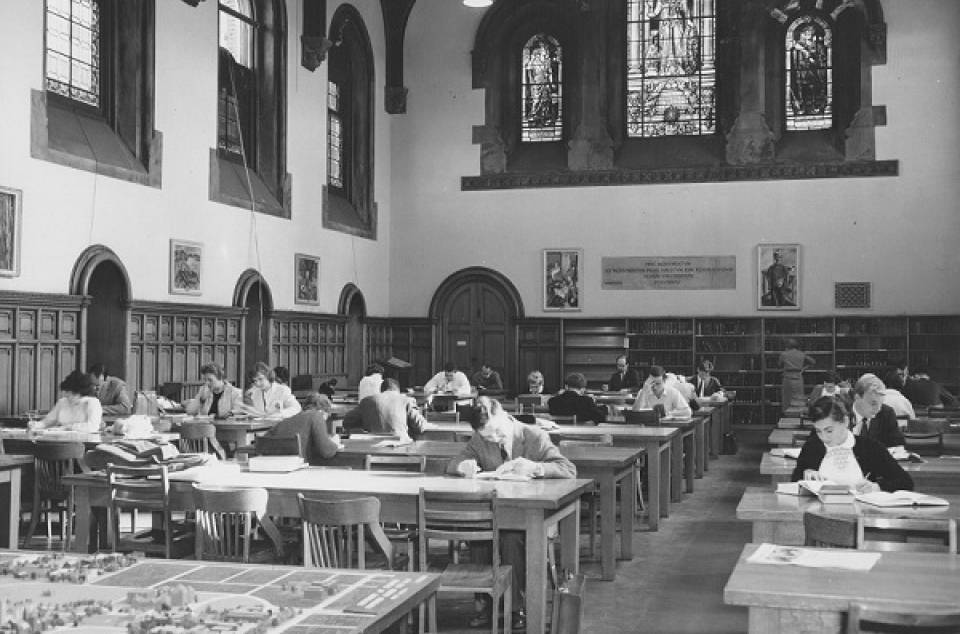 Students reading at tables and desks, with stained glass windows above