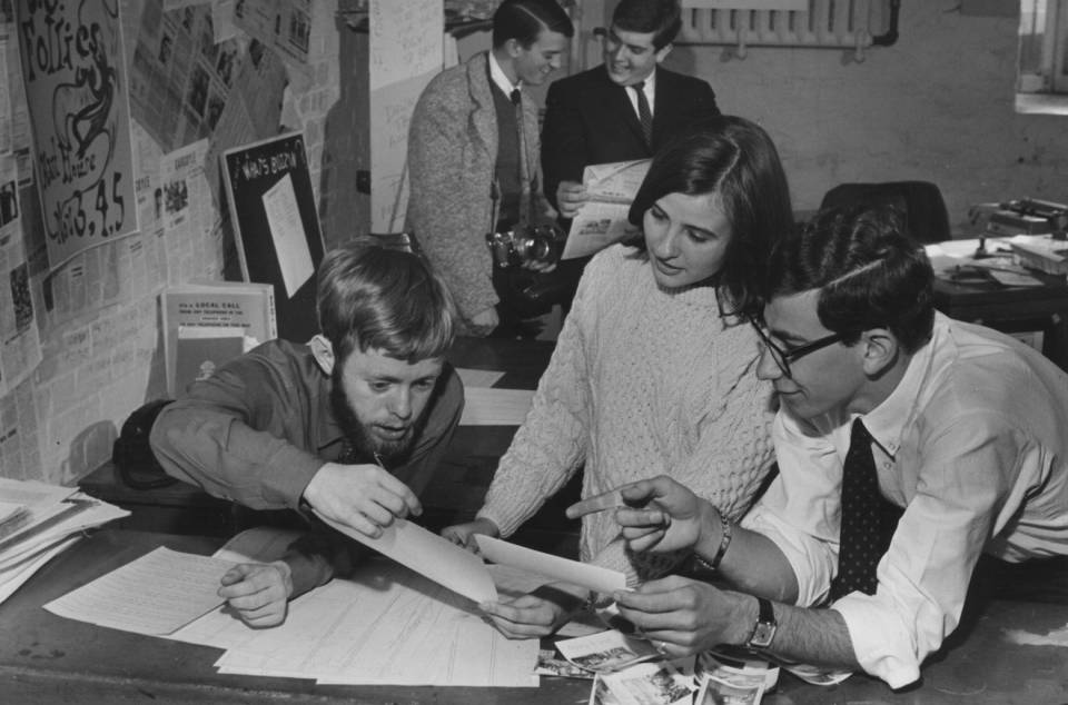 four men and one woman working on a magazine