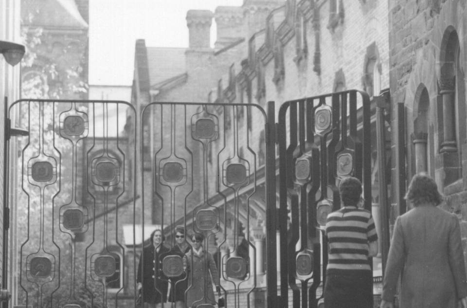 five women about to enter or exit the University College quadrangle through a gate