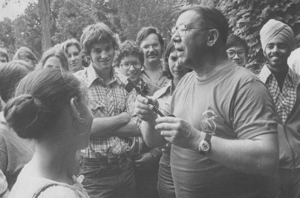 A group of students listening to a professor, who is holding a large key