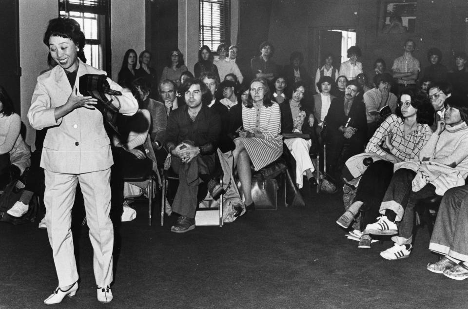 A woman performing opera, and an audience watching