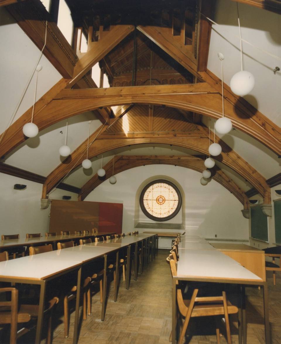 room with three rows of desks and a round stained-glass window