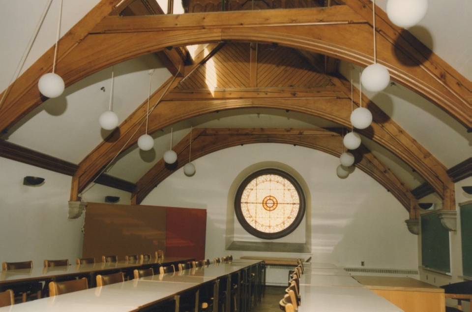 room with three rows of desks and a round stained-glass window