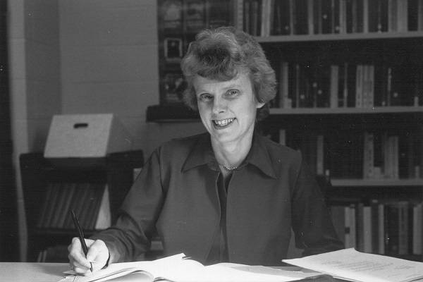 Ingrid Epp sitting at a desk, smiling, with bookshelves behind her