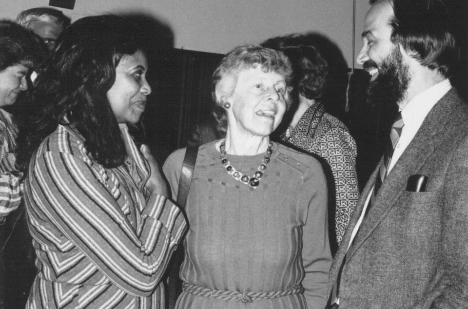 Two women in conversation with Principal Peter Richardson at a reception.