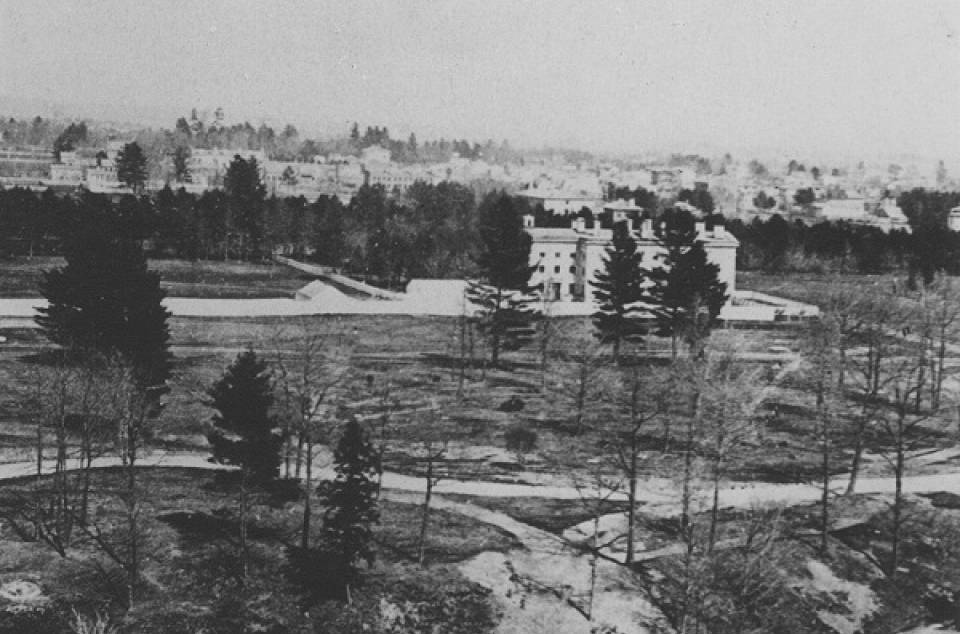 Moss Hall, fields and trees in foreground, distant buildings in background