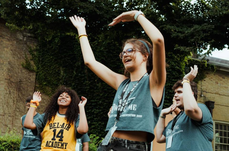 Students with hands raised in Orientation