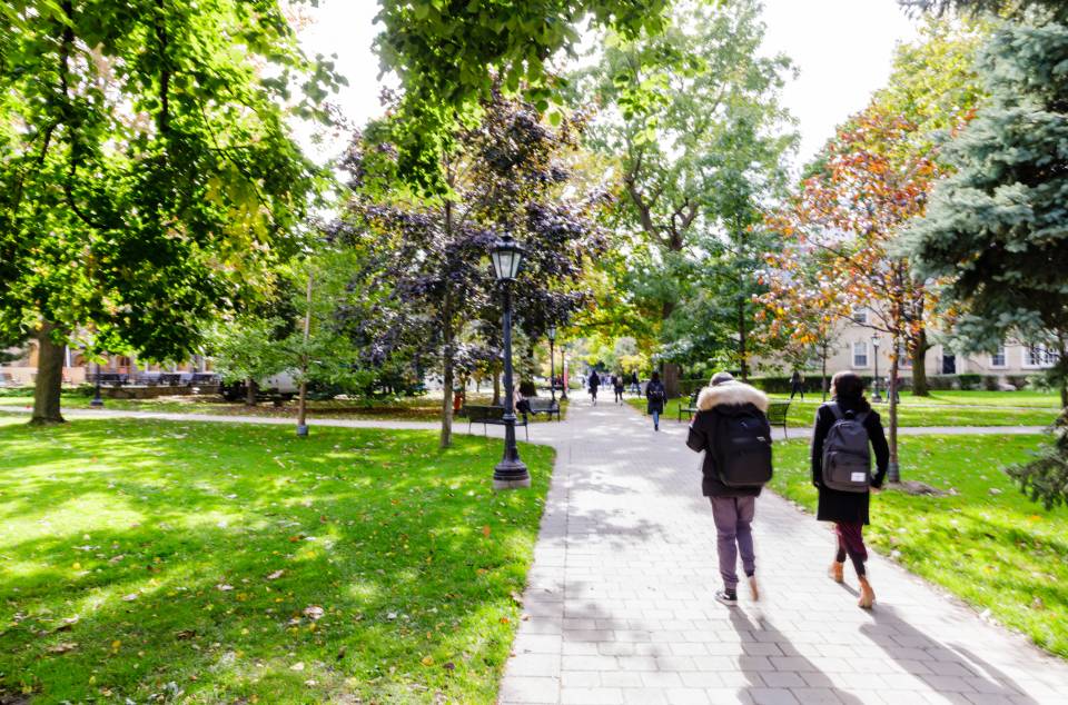 Two students walk away on a path through the Sir Dan's quad