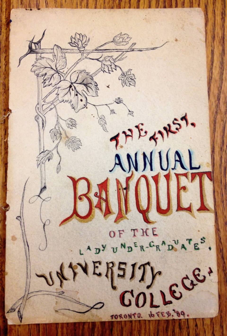 Programme cover illustrated with leaves, with these handwritten words: "THE FIRST ANNUAL BANQUET OF THE LADY UNDERGRADUATES UNIVERSITY COLLEGE TORONTO 16 FEB. '89"