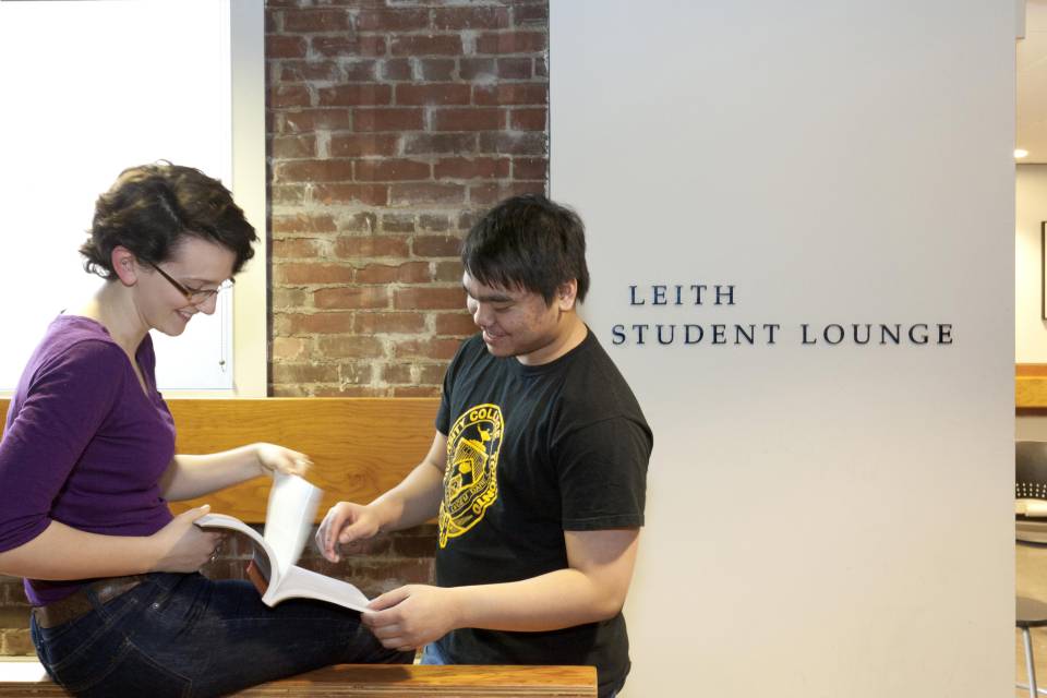 two students flipping a book in the commuter student centre