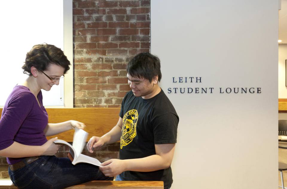 two students flipping a book in the commuter student centre