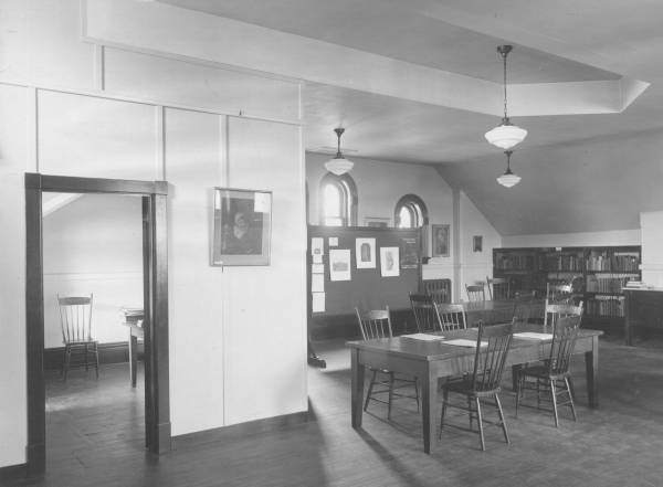 room containing tables, chairs, and bookshelves