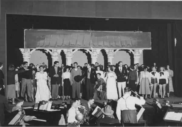 dozens of performers on stage, with musicians and conductor in the foreground