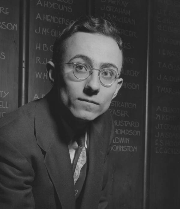 David P. Gauthier in Junior Common Room in front of list of names on wall