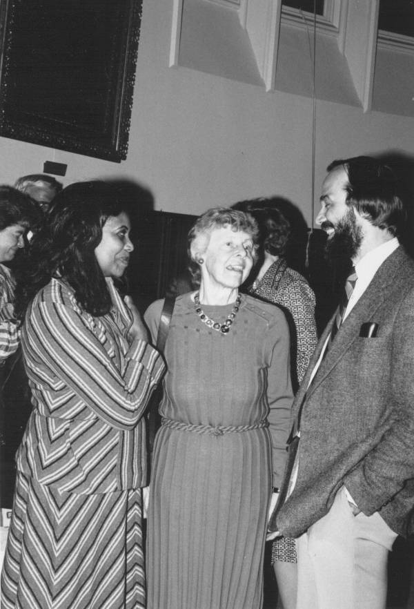 Two women in conversation with Principal Peter Richardson at a reception.