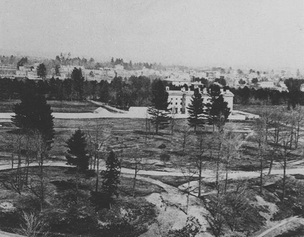 Moss Hall, fields and trees in foreground, distant buildings in background