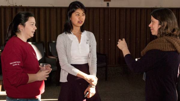 Two smiling students talking to an instructor