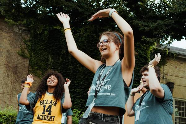 Students with hands raised in Orientation