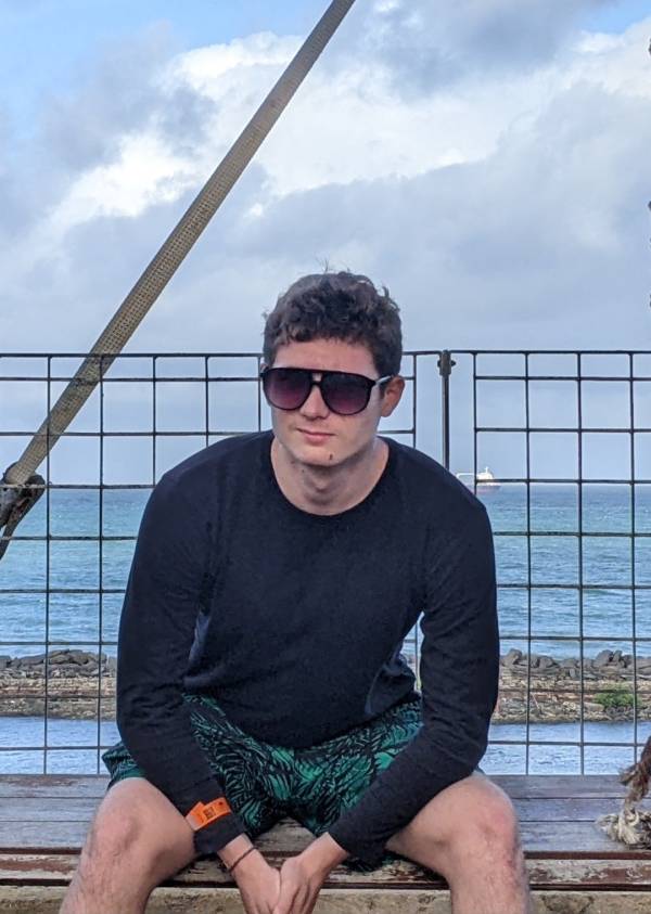 Student Cody Stipelman wearing sunglasses, sitting in front of a waterfront