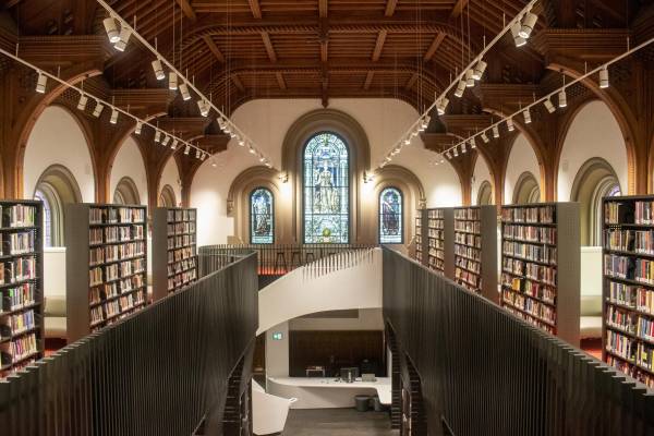 Large library with wooden ceiling, stained glass, and spiral staircase