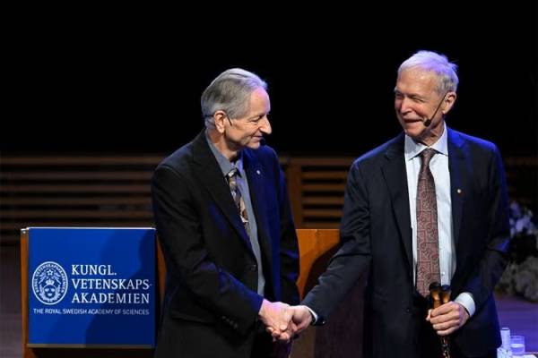 Hinton and John J. Hopfield shake hands after delivering their Nobel Prize lectures.