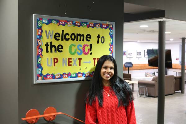 Kiara Andrade in front of the welcome sign of the Commuter Student Centre
