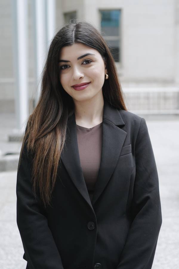 Anahit is wearing a black blazer with a brown shirt. She is smiling at the camera.