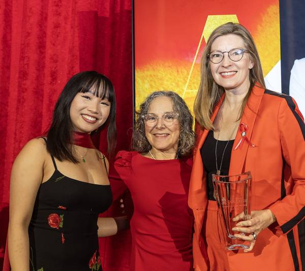 Maev Beaty stands on stage with UC acting Principal Sali Tagliamonte and student and UC lit president Kristina Cổ-Đoàn
