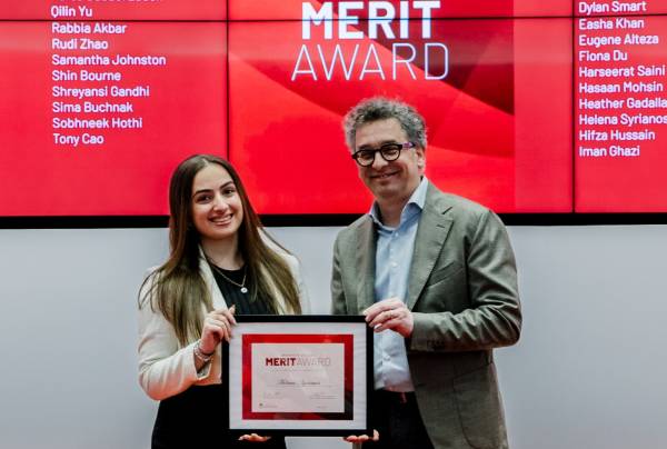 Student holding UC Merit Award Plaque with Principal Markus Stock