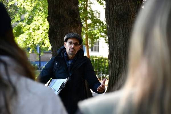 Alan Ackerman speaking beside tree with clipboard