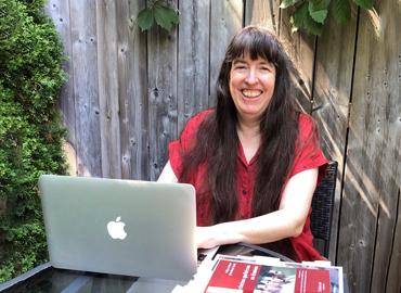 UC Librarian Margaret Fulford smiling in front of her laptop