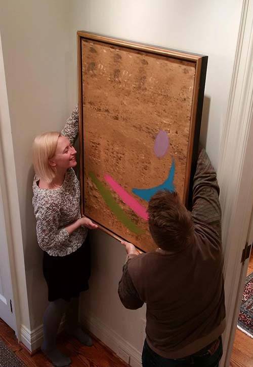 Sarah Stanners and project photographer Craig Boyko carefully rehang a Jack Bush painting