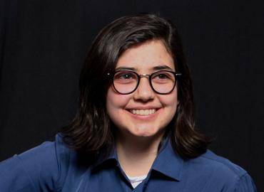 Headshot of Patricia Stewart smiling at camera, with black glasses, and blue shirt.