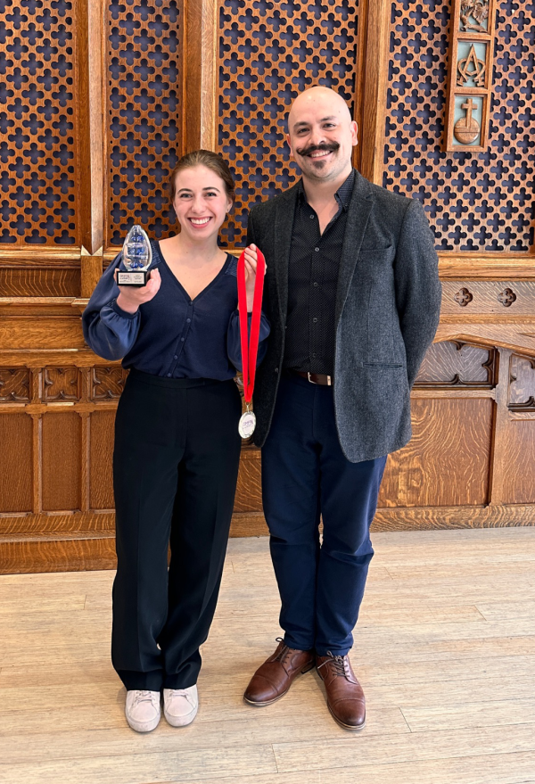 Elzbieta holding medal and trophy beside guitar teacher