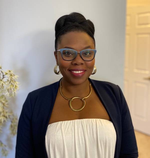 Image of professor Temitope Adefarakan. She is smiling at the camera, wearing a blue blazer with a white top.