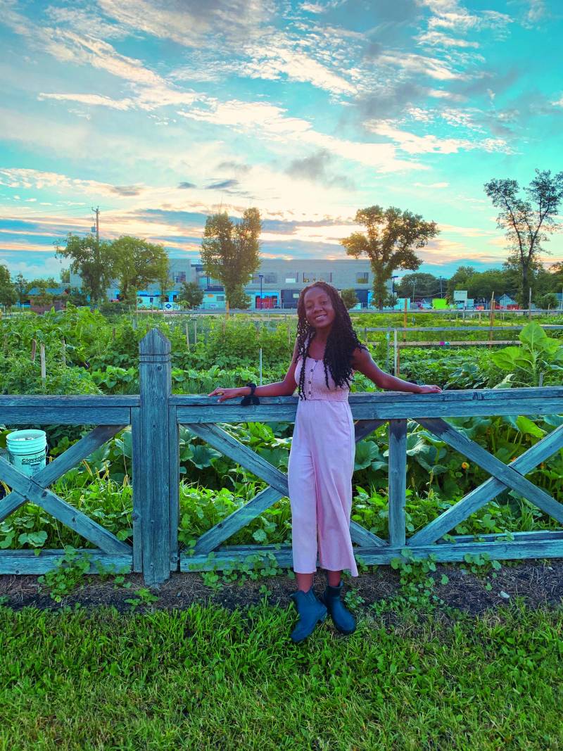 Sophia standing along a fence with a beautiful field behind her