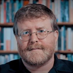 Anderson Todd, staring at the camera, wearing glasses and a black shirt.