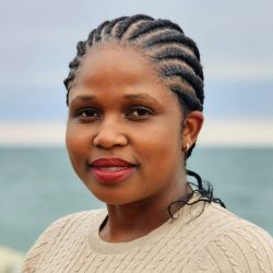 headshot of Cyndirela Chadambuka, wearing a light brown shirt, looking at the camera.