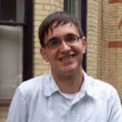Jarret Welsh, Smiling at the camera, with black glasses and a light blue shirt on.