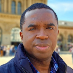 Headshot of Izuchuku Nwankwo, wearing a blue shirt and jacket.