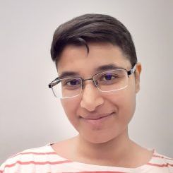 Naveen Minai headshot, smiling at the camera with a orange whit striped shirt, and glasses on.