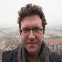 Sean Mills headshot, with foggy background, wearing a grey scarf, black jacket and glasses.